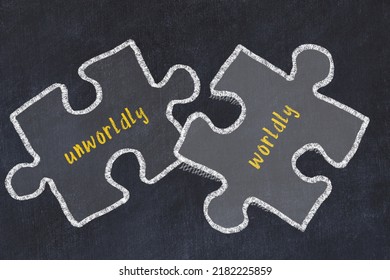 Ploblem solving. Chalk sketch of two puzzles with words unworldly and worldly on black chalkboard