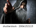 Portrait closeup of a wise Warlock old hooded wizard posing ready to cast an enchanted powerful spell  with a blue gradient background. 3d rendering