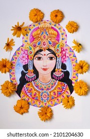 A portrait of the goddess of beauty and wealth Lakshmi with flowers in a crown and ornaments is drawn on paper. A wreath of yellow fresh flowers around the image for Diwali ethnic design.