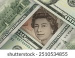 Portrait of the Queen of Great Britain on a pound sterling bill peeks out from under dollar bills. Foreign exchange market. Finance concept