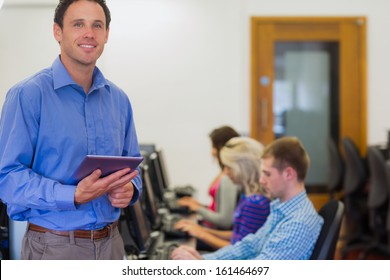 Portrait of a smiling teacher with young college students using computers in the computer room - Powered by Shutterstock