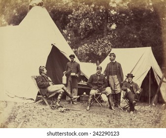 Posing for the camera, a White officer faces his young Black servant, who is holding bottle and cake. Displays the good life available in the Union Camps. November 1862 photo by Alexander Gardner. - Powered by Shutterstock