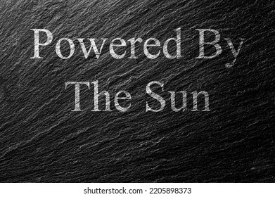 Powered By The Sun Chalk Text On Black Stone Slab