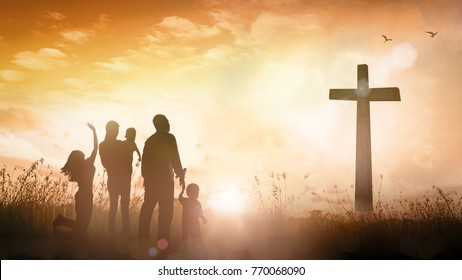 Praise and worship concept: Silhouette christian family looking for the cross on autumn sunrise background