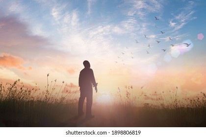 Praise And Worship God Concept: Silhouette Of Healthy Man Standing Against Meadow Sunset Background - 3D Illustration