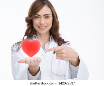 Pretty doctor holding and pointing at a red heart - Powered by Shutterstock