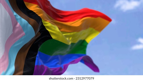 Progress Pride flag waving on a clear day. Black, brown, light blue, pink, and white to the rainbow flag to represent marginalized LGBTQ+ communities. 3d illustration render. Selective focus. - Powered by Shutterstock