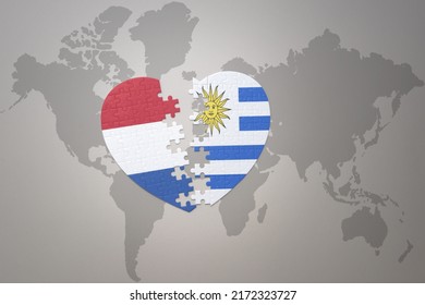 puzzle heart with the national flag of uruguay and netherlands on a world map background.Concept. 3D illustration