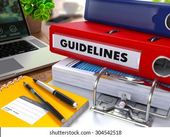 Red Ring Binder With Inscription Guidelines On Background Of Working Table With Office Supplies, Laptop, Reports. Toned Illustration. Business Concept On Blurred Background.