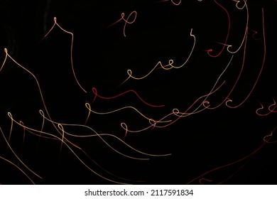 Red Yellow Orange Curls On A Black Background. Abstraction. Drawing With Light. Photo Effect.