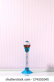 A Regular Blue Vintage Gumball Dispenser Machine Made Of Glass And Reflective Plastic With Multicolored Gumballs In A Retro Candy Store Background With Pink Striped Wallpaper Background