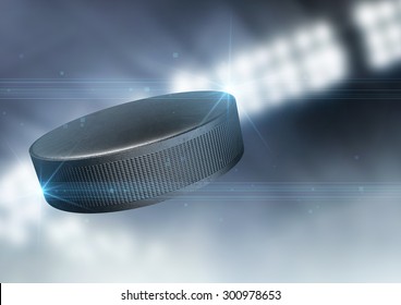 A regular ice hockey puck flying through the air on an indoor stadium background during the night