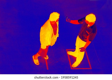 Remote Thermometer, Body Temperature Meter In Connection With Coronavirus Quarantine. Remote Temperature Measurement Using Thermal Imager Helps To Identify Patients. Blurred Unrecognizable People.