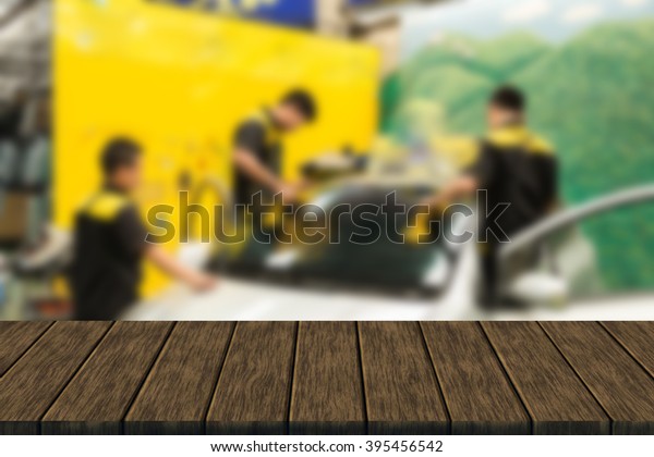 Repairman is\
repairing windshield of the car (blur background with wood table\
top for display or montage your\
product)