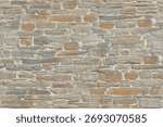 Rough stone wall composed of irregular and flat stones, of variable sizes and shapes, tightly fitted together. The stones have a palette of gray and earthy brown tones
