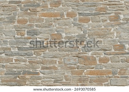 Rough stone wall composed of irregular and flat stones, of variable sizes and shapes, tightly fitted together. The stones have a palette of gray and earthy brown tones