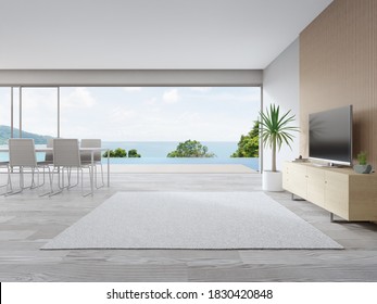 Rug On Wooden Floor Of Large Living Room And Dining Table Near TV In Modern Beach House Or Luxury Pool Villa. White Home Interior 3d Rendering With Sea View.