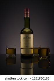Russia, Surgut, December 7, 2018: A bottle of Glenlivet whiskey 12-year-old with glasses filled with this drink, on a dark background. 3D-visualization.
