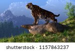 A saber-toothed cat stands atop a boulder on a grassy hill. The ferocious prehistoric predator looks down into a tree filled ice age valley rimmed with snow covered mountains. 3D Rendering
