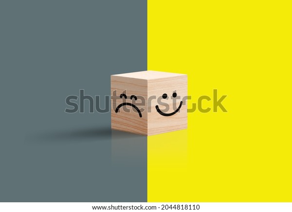 Sad happy concept. smiley face and sad face icon on wood\
cube, Service rating, satisfaction concept, and Optimism pessimism\
concepts. 3d Wooden Cub. Bright yellow and dark background. 3D\
illustration 