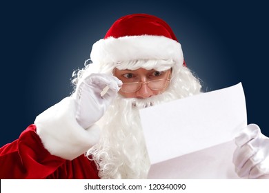 Santa Claus holding and reading a letter to him - Powered by Shutterstock