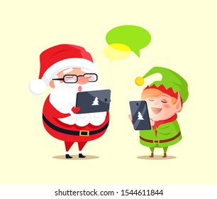 Santa And Elf Cartoon Characters Chatting With Help Of Modern Computer Technologies. Father Christmas Use Tablet And Little Helper With Smartphone Raster