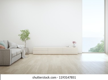 Sea View Living Room Of Luxury Summer Beach House With TV Stand And Wooden Cabinet. Empty White Concrete Wall Background In Vacation Home Or Holiday Villa. Hotel Interior 3d Illustration.