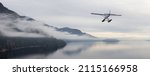 Seaplane flying over Canadian Mountain Nature Landscape on the Pacific West Coast. Cloudy and fog Winter Day. 3d Rendering Airplane Adventure Concept. Howe Sound, British Columbia, Canada.