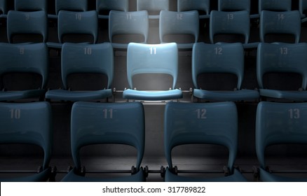 A Section Of Numbered Stadium Seating Set In Rows Coin The Dark With One Seat  Being Singled Out By A Spotlight 