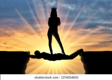 Selfish Woman With A Crown Standing On A Man In The Form Of A Bridge Over An Abyss. Concept Of Selfishness And Personal Interest