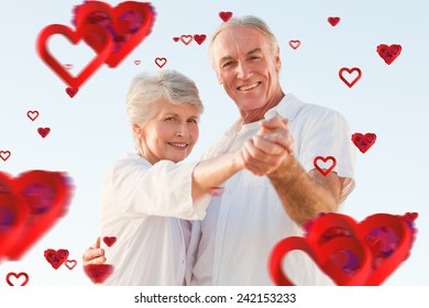 Senior couple dancing on the beach against love heart pattern - Powered by Shutterstock