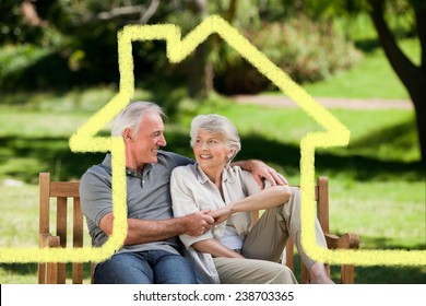 Senior couple sitting on a bench against house outline - Powered by Shutterstock