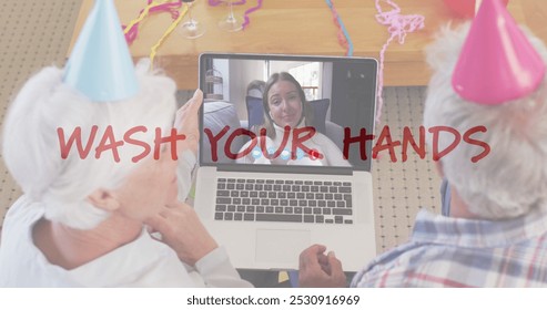 Senior couple video chatting with a teenage girl on a laptop. They celebrate remotely with party hats and a Wash Your Hands message. - Powered by Shutterstock