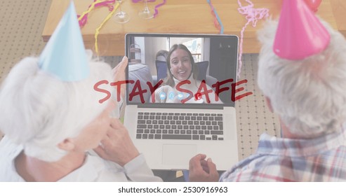 Senior couple wearing party hats video chatting with a young woman on a laptop. The message Stay Safe overlays the scene, suggesting a virtual celebration during a time of caution. - Powered by Shutterstock