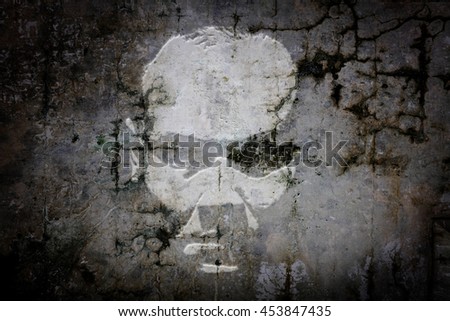 Shadow apparition of an eerie man face on a grungy concrete wall.
