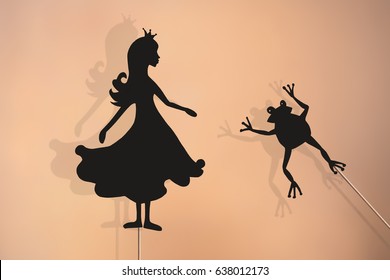 Shadow Puppets Of Princess And Frog With Soft Glowing Screen Of Shadow Theater In The Background.