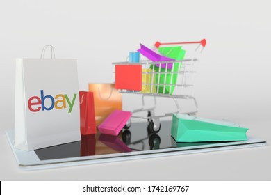 Shopping cart on a tablet computer and paper bag with eBay logo. Editorial e-commerce related 3D rendering
