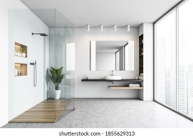 Shower Cabin In White Bathroom With Sink And Big Mirror With Shelves. Open Space Bathroom With Grey Floor And Plant. Big Window With View On Skyscrapers, 3D Rendering No People