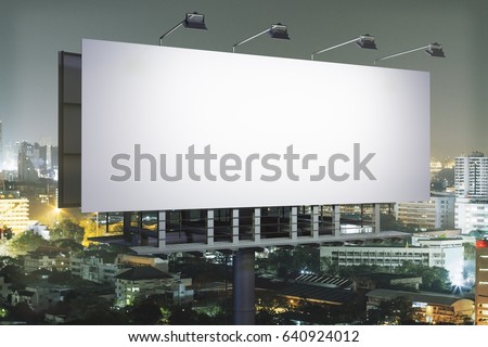 Side view of empty billboard on illuminated night city background. Advertisement concept. 3D Rendering