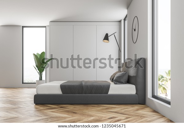 Side view of master bedroom with white walls, wooden floor, gray and