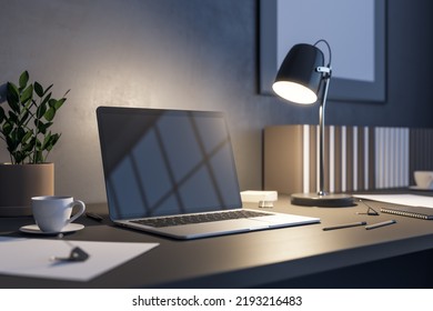 Side View On Blank Dark Laptop Screen With Copyspace For Your Text Or Logo On Dark Wooden Table With Tea Cup, Stylish Illuminated Lamp And Flower Pot In The Evening Office. 3D Rendering, Mockup