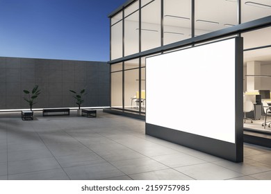 Side View On Outdoor Blank White Billboard On Grey Floor And Stylish Street Benches Near Modern Business Center Building With Glass Walls In The Evening. 3D Rendering, Mockup