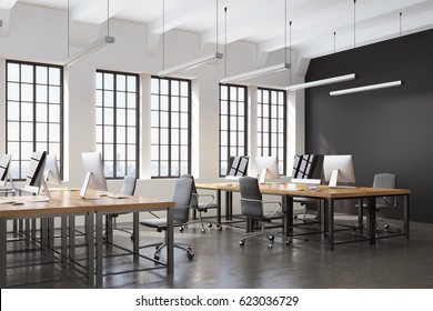 Side view of an open space office with a black wall, many tables with computers on them and a concrete floor. 3d rendering.