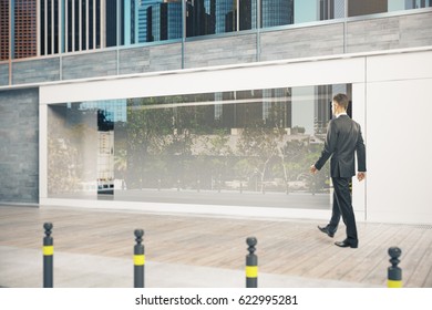 Side view of young man walking by glass shopfront during daytime. Ad concept. Mock up, 3D Rendering