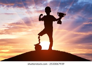 A silhouette of a boy with a prosthetic leg, standing tall on a hilltop with a soccer ball and trophy, represents the achievement of a dream. Hope and inspiration For disabled people - Powered by Shutterstock