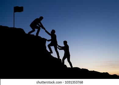 Silhouette of businessman helping each other hike up a mountain at sunrise. Business, teamwork, goal, success and help concept. Vintage filter.