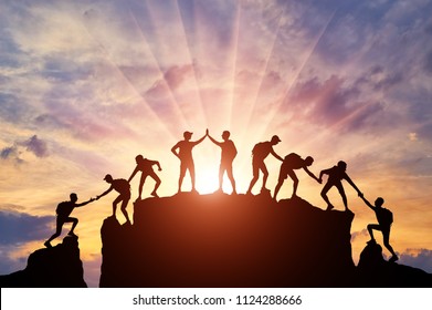 Silhouette of climbers who climbed to the top of the mountain thanks to mutual assistance and teamwork. Conceptual scene of a team of alpinists