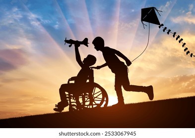 A silhouette of a disabled boy in a wheelchair reaching for the sky with a toy airplane, while his friend runs alongside holding a kite. Childhood friendship, support with disabled people - Powered by Shutterstock