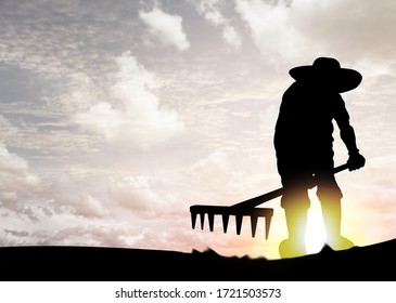 Silhouette Of A Farmer Raking The Earth With A Hoe For The Philosophical Concept: You Reap What You Sow. 