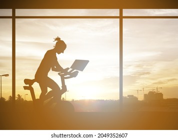 Silhouette of a girl exercise on a stationary bicycle machine in an indoor gym overlooking a sunset cityscape for the concept of urban workout.  - Powered by Shutterstock